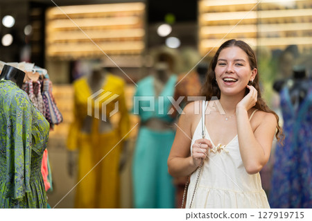 Young girl in white dress is looking for something at street market - looking at goods with interest Young girl in white dress is looking for something at street market - looking at goods with interest 127919715