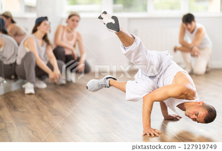 Young guy breakdancing in front of group members watching him 127919749