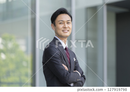 40 多歲的商人微笑著，雙臂交叉，看著鏡頭 127919798