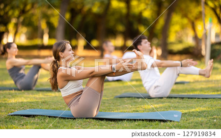 Girl performing half boat pose during yoga session outdoors 127919834