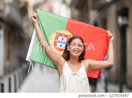 Young woman with Portuguese flag on city street 127919847
