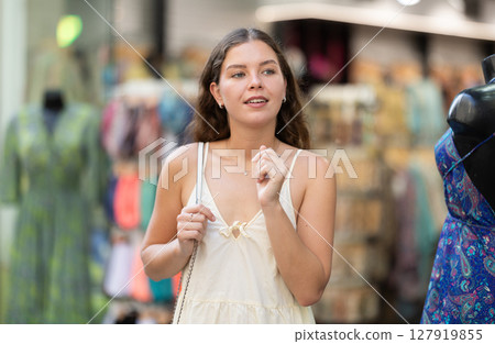 Young girl in white dress is looking for something at street market - looking at goods with interest 127919855