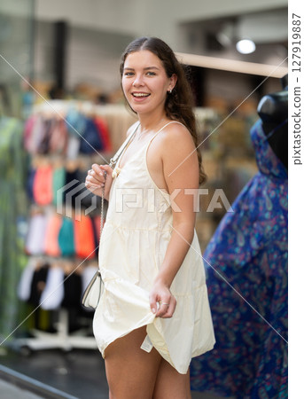 Young girl in white dress is looking for something at street market - looking at goods with interest 127919887