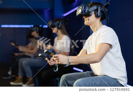 Guy with handheld controllers and VR glasses playing virtual game 127919891
