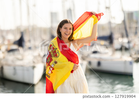 Young woman wrapped in Spanish flag in port Young woman wrapped in Spanish flag in port 127919904