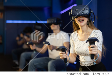 Excited young woman in VR goggles having fun in virtual reality room Excited young woman in VR goggles having fun in virtual reality room 127919906
