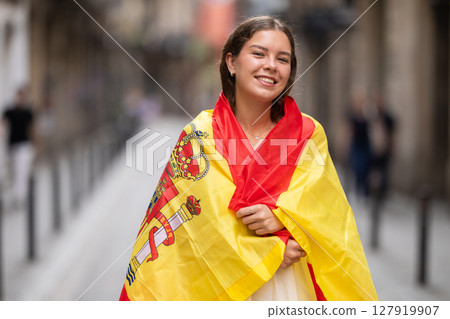 Young woman wrapped in Spanish flag on city street 127919907