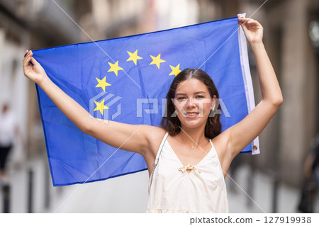 Woman waving European Union flag on street of summer European city Woman waving European Union flag on street of summer European city 127919938