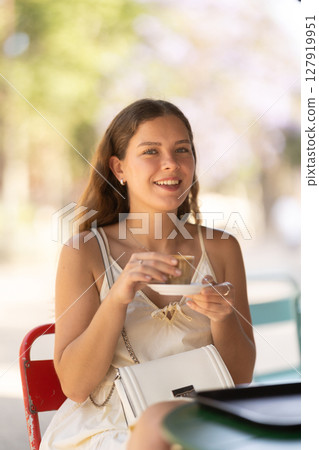 Smiling woman drinking espresso coffee while sitting on terrace of street cafe 127919951
