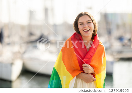 Young woman wrapped in LGBT flag at port 127919995