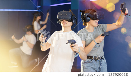 Young couple with handheld controllers and VR glasses playing game Young couple with handheld controllers and VR glasses playing game 127920018