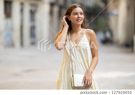 Young woman looks around on city street Young woman looks around on city street 127920050