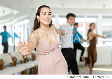 Smiling girl rehearsing upbeat jive with partner in dance studio 127920057