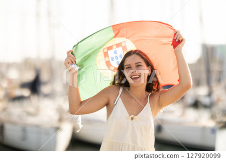 Woman waving Portugal flag against seaport and yachts 127920099