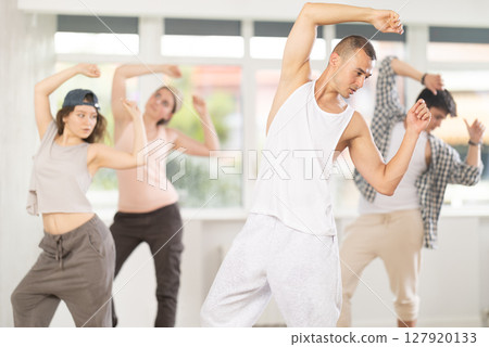 Young guy practicing basic hip hop moves in training hall 127920133