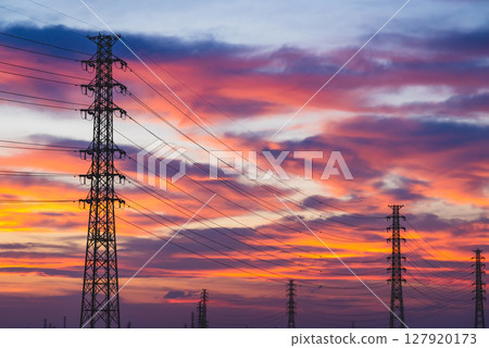A sunset-tinted sky and a row of power transmission towers - High saturation matte finish 127920173