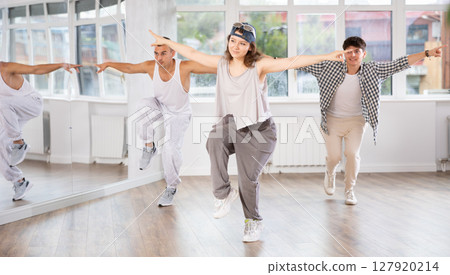 Young girl standing performs basic hip hop movements in front of group of students Young girl standing performs basic hip hop movements in front of group of students 127920214