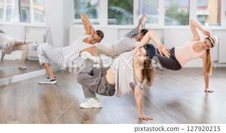 Concetrated guys and girls studying movement of contemporary dance in classroom with his friends Concetrated guys and girls studying movement of contemporary dance in classroom with his friends 127920215