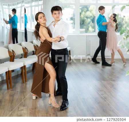 Hispanic guy enjoying merengue with female partner in dance class 127920304