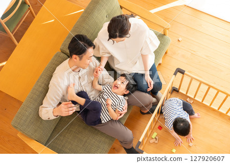 A young couple with a child playing in the living room 127920607