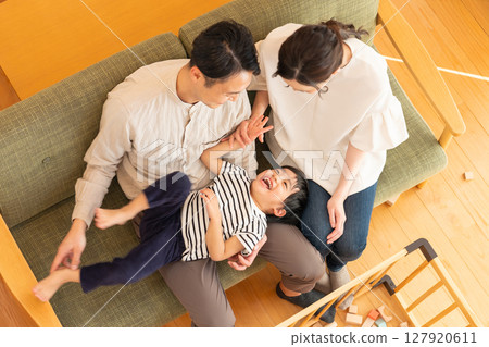 一對年輕夫婦帶著一個孩子在客廳玩耍 127920611