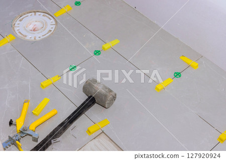 Grey tiles are being set with spacers tools on floor for tile installation in home renovation 127920924