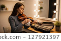 A woman preparing her violin in the dressing room before a concert 127921397