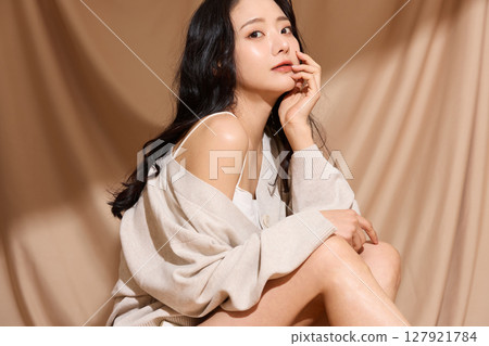 Luxurious beauty portrait of a young woman photographed against a beige fabric background 127921784