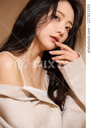Luxurious beauty portrait of a young woman photographed against a beige fabric background 127921810
