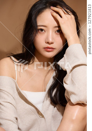 Luxurious beauty portrait of a young woman photographed against a beige fabric background 127921813