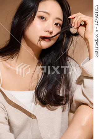 Luxurious beauty portrait of a young woman photographed against a beige fabric background 127921815