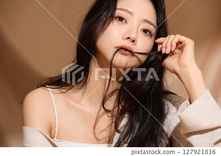 Luxurious beauty portrait of a young woman photographed against a beige fabric background 127921816
