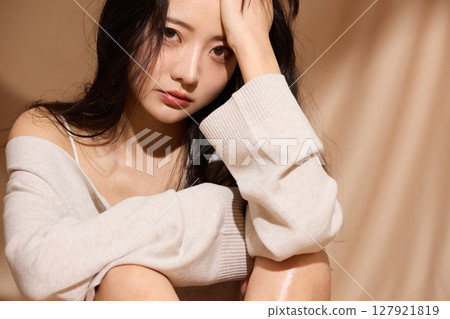 Luxurious beauty portrait of a young woman photographed against a beige fabric background 127921819
