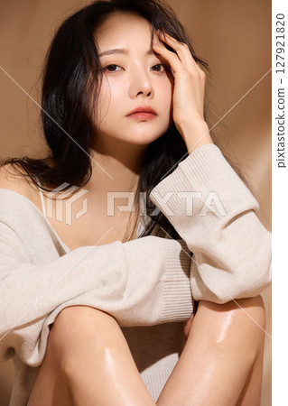 Luxurious beauty portrait of a young woman photographed against a beige fabric background Luxurious beauty portrait of a young woman photographed against a beige fabric background 127921820