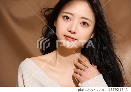 Luxurious beauty portrait of a young woman photographed against a beige fabric background 127921841