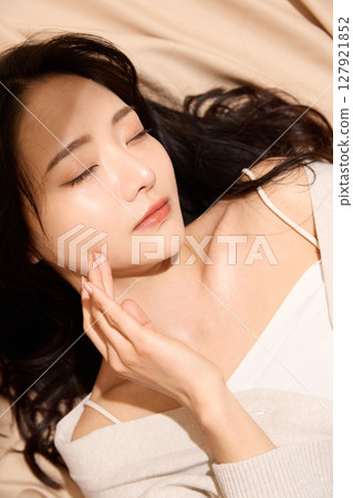 Luxurious beauty portrait of a young woman photographed against a beige fabric background 127921852
