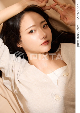 Luxurious beauty portrait of a young woman photographed against a beige fabric background Luxurious beauty portrait of a young woman photographed against a beige fabric background 127921856