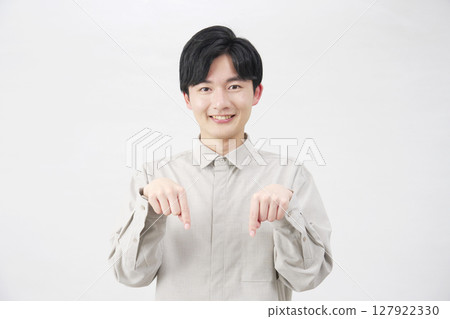 Man in his 20s pointing down, white background 127922330