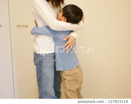 一位母親稱讚並擁抱她的孩子 一位母親稱讚並擁抱她的孩子 127923129