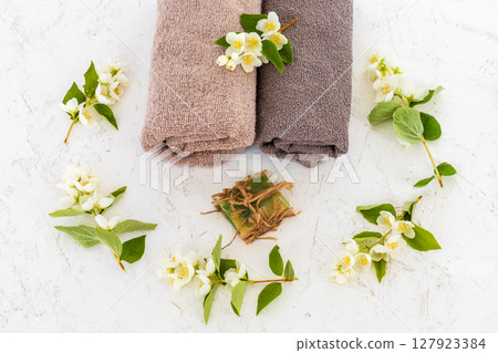 Towels with body care products and branches of jasmine on the white background. 127923384