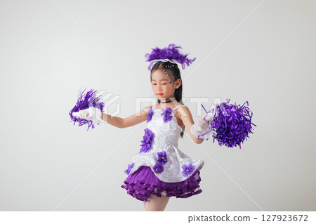 Smiling kid cheerleader in purple and white uniform, holding pom-poms. Studio shot with a clean white background. Youthful energy and celebration. cheerleader kid Smiling kid cheerleader in purple and white uniform, holding pom-poms. Studio shot with a clean white background. Youthful energy and celebration. cheerleader kid 127923672