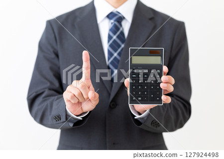 一位身穿西裝的中年男性商人拿著計算器，用食指指著 127924498