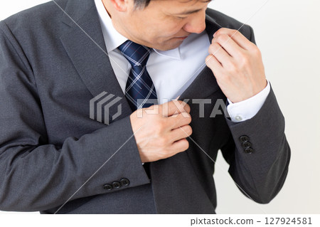 A middle-aged male businessman in a suit who is concerned about body odor 127924581