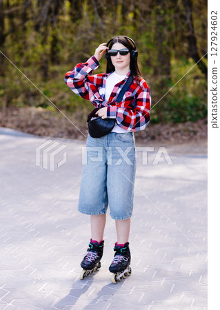 Young woman roller skating in a park during spring enjoying a sunny day 127924602