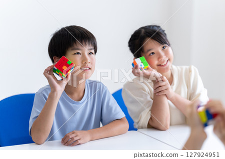 Children trying to solve the educational toy Rubik's Cube 127924951