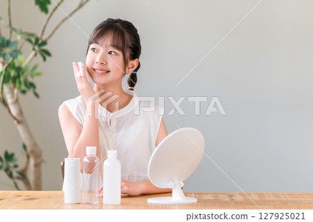 Children, girls, elementary school students, junior high school students putting on makeup while looking in the mirror 127925021