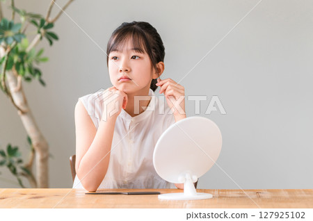 Elementary school and junior high school girls with dissatisfied expressions in front of the mirror Elementary school and junior high school girls with dissatisfied expressions in front of the mirror 127925102