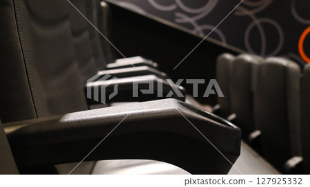 Rows of empty black leather cinema seats with cup holders Rows of empty black leather cinema seats with cup holders 127925332