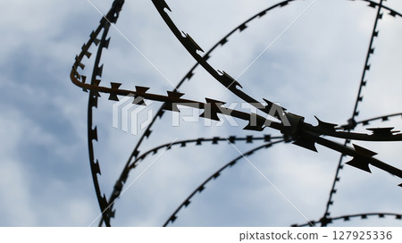 Prison wall and barbed wire under blue sky Prison wall and barbed wire under blue sky 127925336