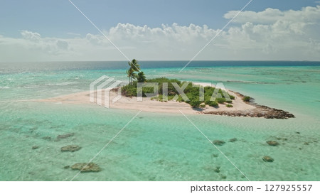 A stunning aerial view captures a secluded tropical island surrounded by vibrant turquoise waters. The sandy shore complements the greenery, showcasing nature's beauty. A stunning aerial view captures a secluded tropical island surrounded by vibrant turquoise waters. The sandy shore complements the greenery, showcasing nature's beauty. 127925557